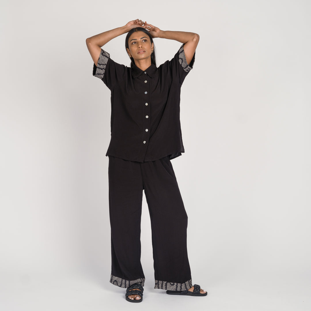 Model in a black matching pant set with shibori accent details on the cuffs, standing against a neutral background