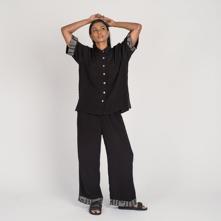 Model in a black matching pant set with shibori accent details on the cuffs, standing against a neutral background